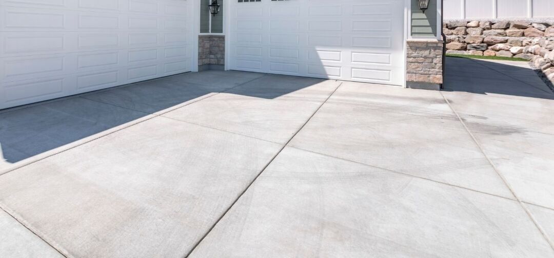 Smooth residential concrete driveway installed in front of a three-car garage, showcasing durable concrete installation for a modern Mid-Dallas, OR home.