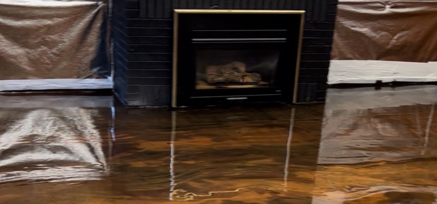 A glossy epoxy floor reflects a fireplace and protected walls, showcasing a clean, polished surface after proper epoxy floor maintenance.